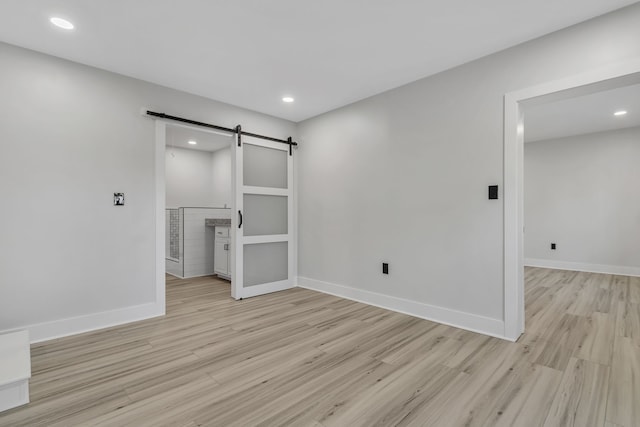 empty room with a barn door and light wood-type flooring