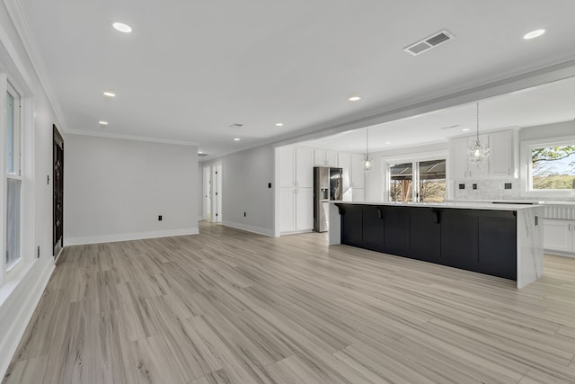 kitchen with a large island, white cabinetry, a chandelier, and light wood-type flooring