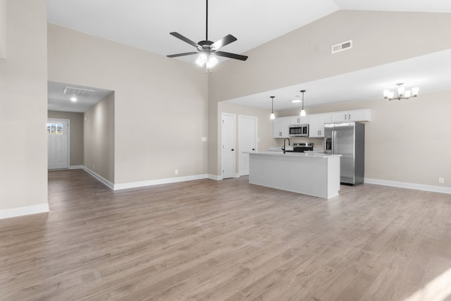 unfurnished living room with high vaulted ceiling, sink, ceiling fan with notable chandelier, and light wood-type flooring