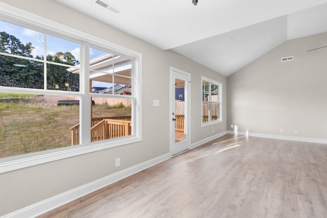 spare room with vaulted ceiling, a healthy amount of sunlight, and light wood-type flooring