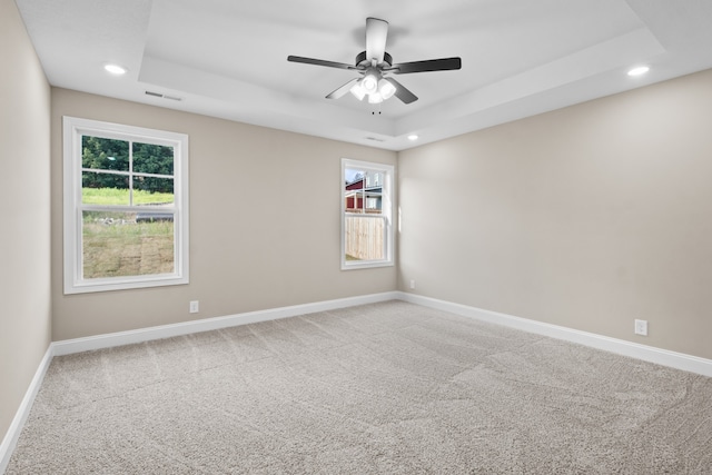 empty room with carpet, ceiling fan, and a tray ceiling