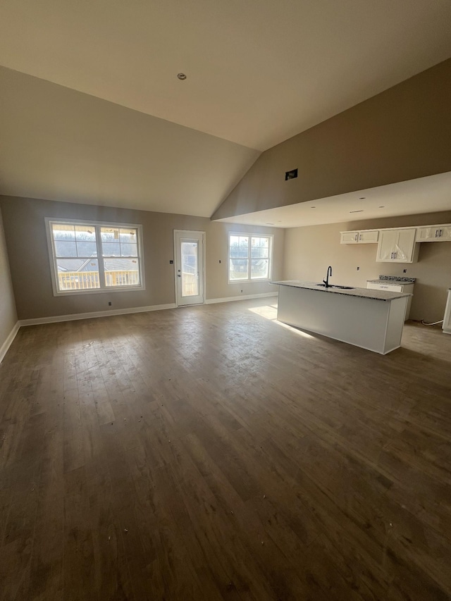 unfurnished living room with dark wood-type flooring, sink, and vaulted ceiling