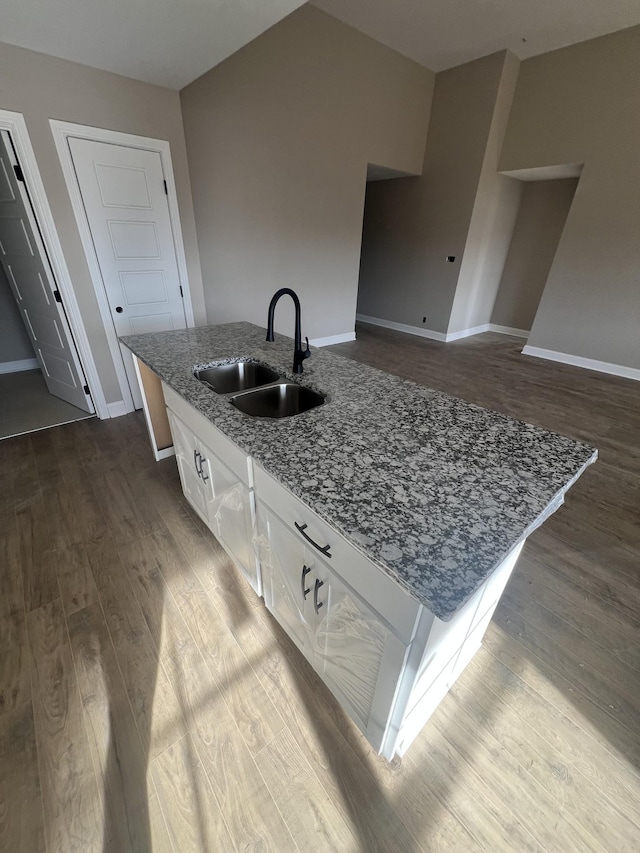 kitchen featuring sink, an island with sink, white cabinets, and stone counters