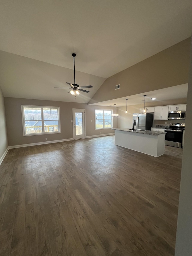 unfurnished living room with dark wood-type flooring, lofted ceiling, visible vents, and baseboards