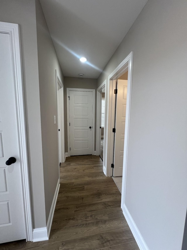 corridor with dark wood-style floors and baseboards