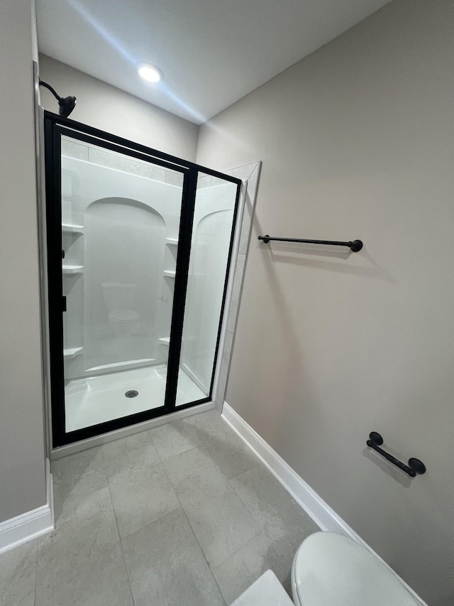 bathroom with toilet, a shower stall, and baseboards