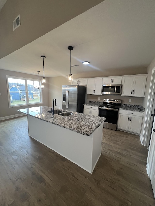 kitchen with stainless steel appliances, dark wood-type flooring, a sink, and light stone counters