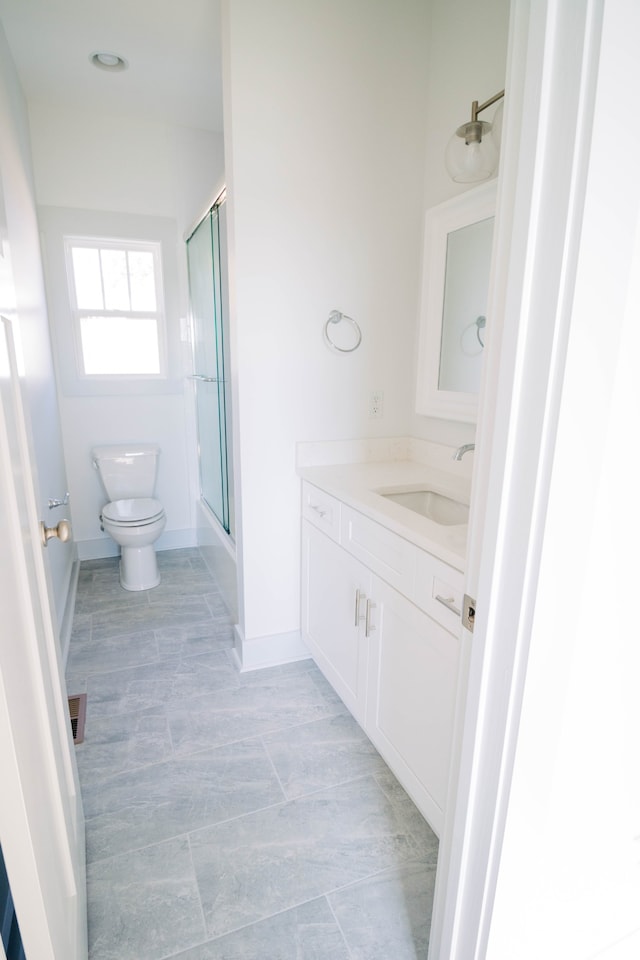 bathroom with vanity, toilet, and a shower with shower door