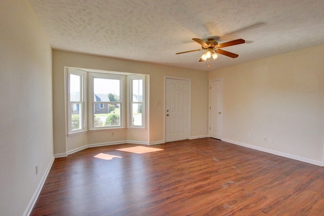 unfurnished room with a textured ceiling, ceiling fan, and dark hardwood / wood-style flooring