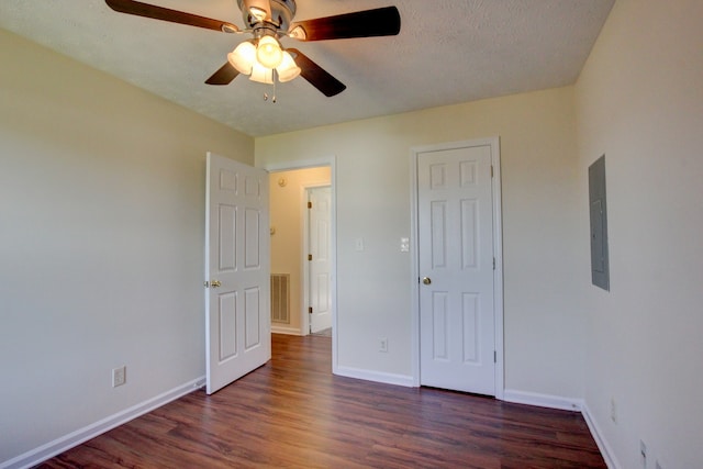 unfurnished bedroom featuring ceiling fan, electric panel, a textured ceiling, and dark hardwood / wood-style flooring