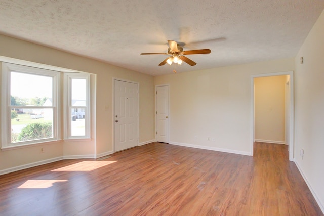 empty room featuring light hardwood / wood-style floors, a textured ceiling, and ceiling fan