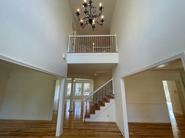 foyer featuring ornate columns, wood-type flooring, a high ceiling, and a chandelier