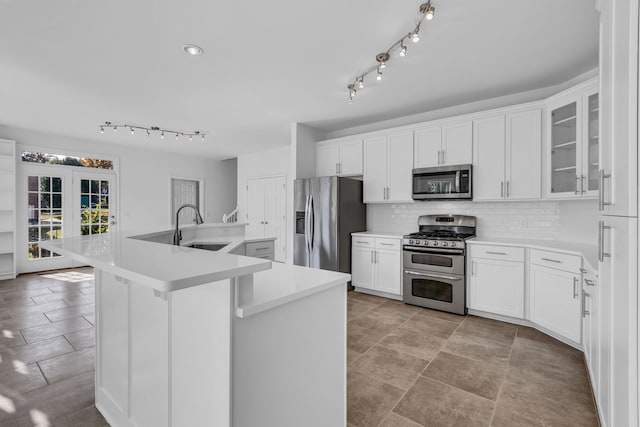 kitchen featuring decorative backsplash, a center island with sink, sink, white cabinets, and appliances with stainless steel finishes