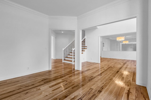 unfurnished living room with crown molding, hardwood / wood-style flooring, and an inviting chandelier