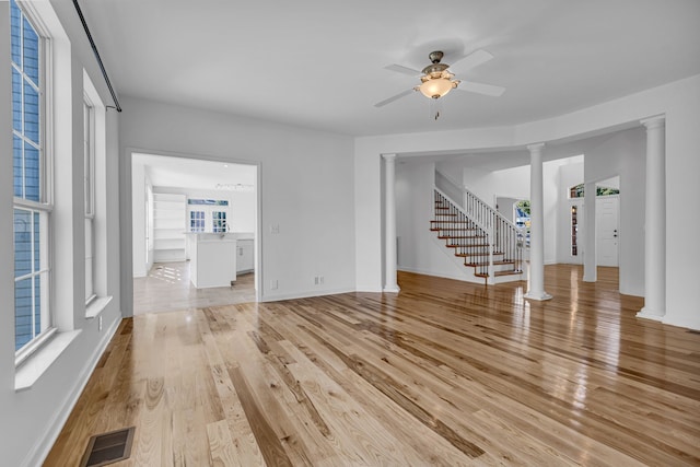 unfurnished living room featuring light hardwood / wood-style flooring, ornate columns, and ceiling fan