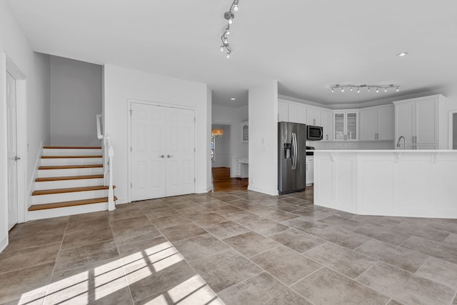 kitchen with appliances with stainless steel finishes, white cabinets, sink, and rail lighting