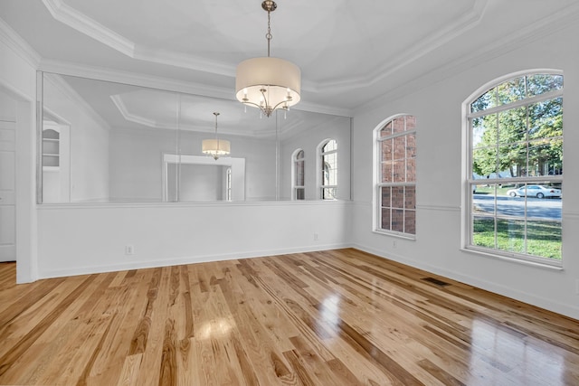 unfurnished dining area with an inviting chandelier, crown molding, light wood-type flooring, and a raised ceiling