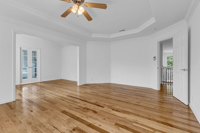 spare room featuring light wood-type flooring, french doors, a tray ceiling, ceiling fan, and crown molding