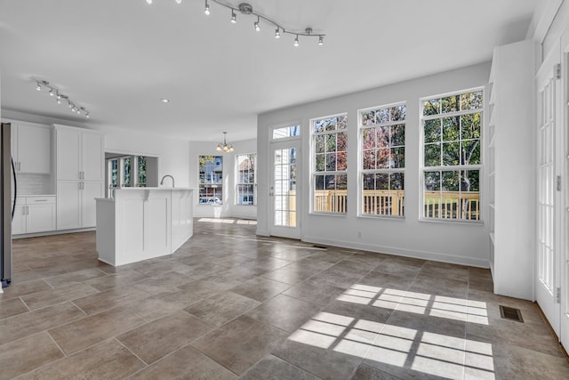 unfurnished living room featuring a chandelier