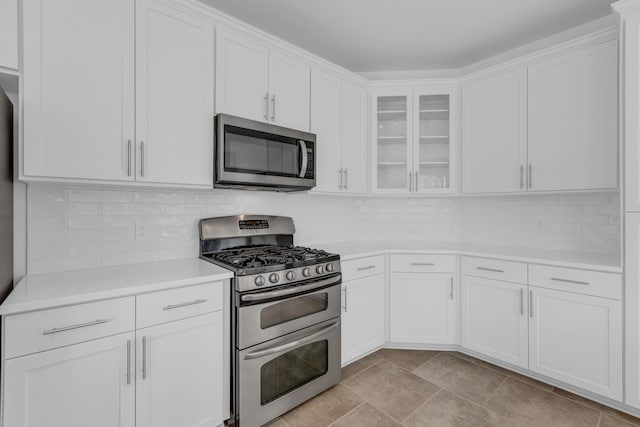 kitchen with appliances with stainless steel finishes, white cabinets, and backsplash