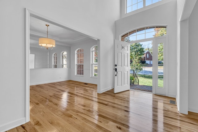 foyer featuring crown molding, wood-type flooring, and a high ceiling