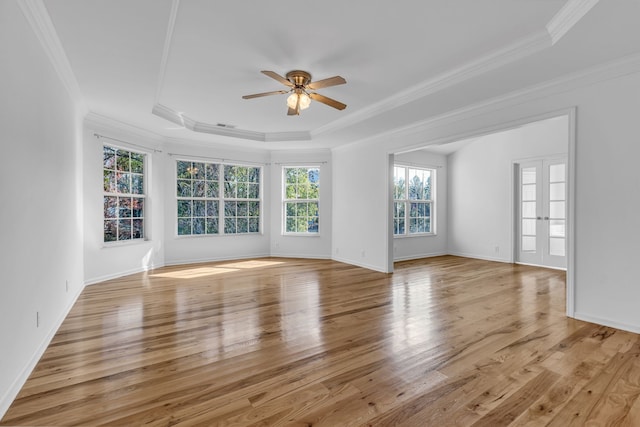 unfurnished room with crown molding, a tray ceiling, light wood-type flooring, and ceiling fan