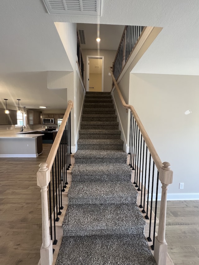 stairway featuring hardwood / wood-style flooring and sink