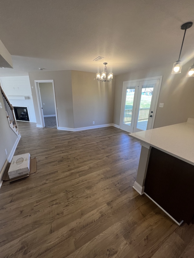 unfurnished living room with dark wood-type flooring and a notable chandelier