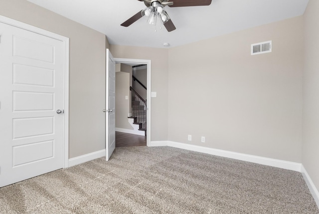 unfurnished bedroom featuring carpet floors, baseboards, visible vents, and a ceiling fan