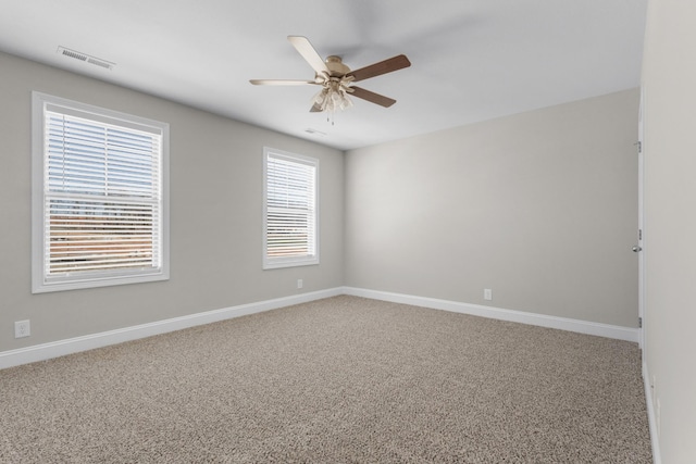 empty room featuring carpet floors, visible vents, baseboards, and a ceiling fan