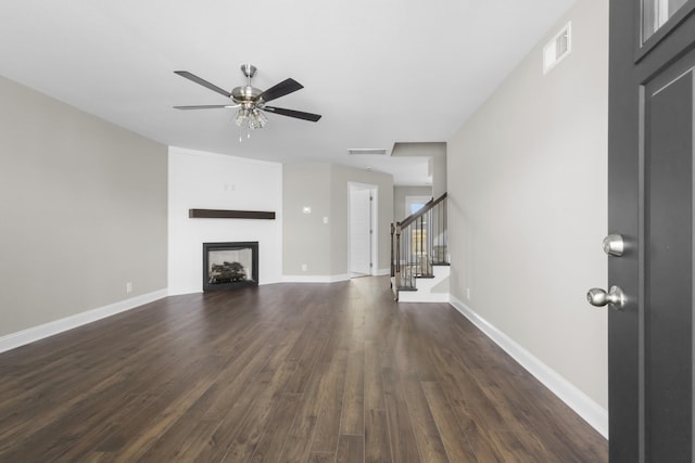 unfurnished living room featuring dark wood finished floors, visible vents, a fireplace, and baseboards