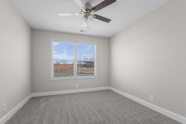 empty room with carpet flooring, ceiling fan, visible vents, and baseboards