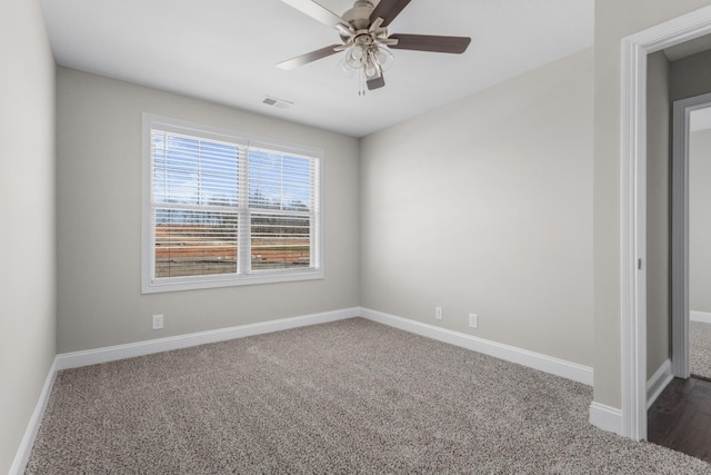 spare room with ceiling fan, dark carpet, visible vents, and baseboards