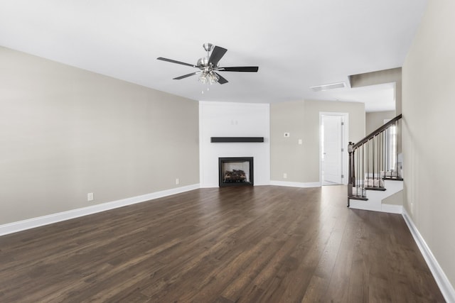 unfurnished living room with dark wood-type flooring, a fireplace, visible vents, baseboards, and stairs