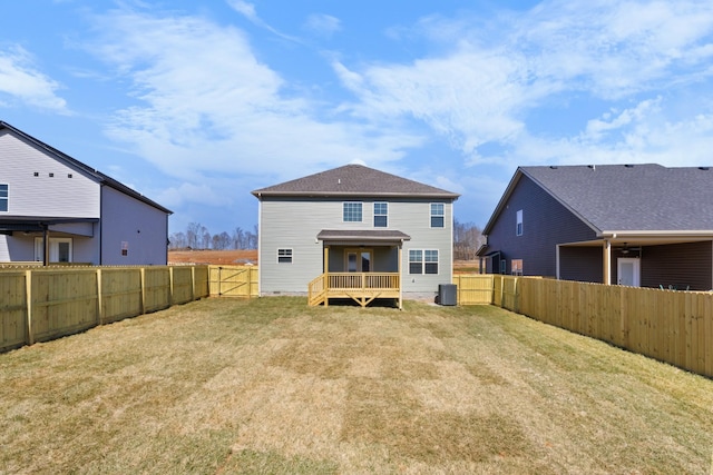 rear view of property with a fenced backyard, a deck, cooling unit, and a yard