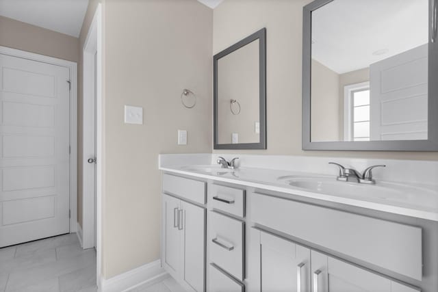 full bath featuring a sink, baseboards, and double vanity