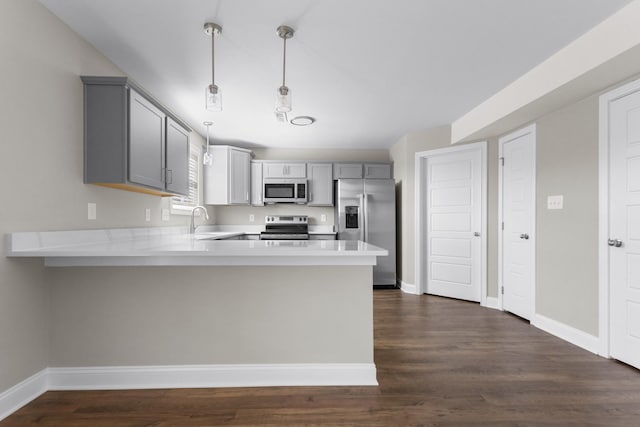 kitchen featuring a peninsula, appliances with stainless steel finishes, a sink, and gray cabinetry