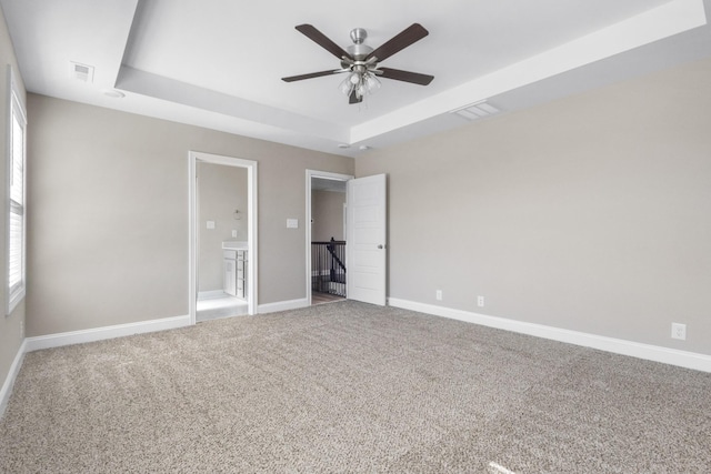 unfurnished bedroom with carpet floors, a raised ceiling, visible vents, and baseboards