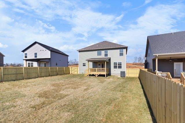 rear view of house featuring central air condition unit, a lawn, a wooden deck, and a fenced backyard