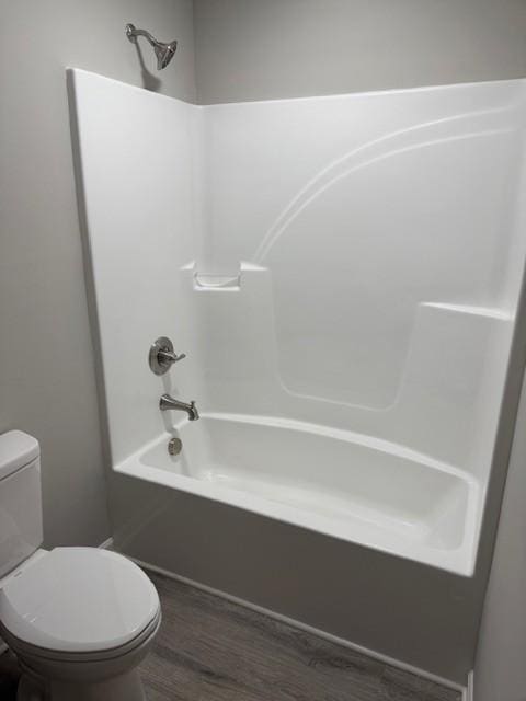 bathroom featuring  shower combination, toilet, and hardwood / wood-style floors