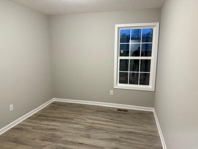 unfurnished room with hardwood / wood-style flooring and a textured ceiling