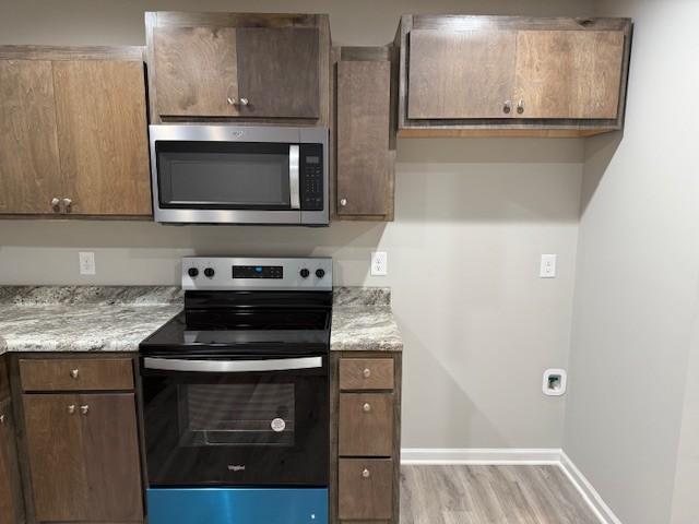 kitchen featuring light stone counters, light hardwood / wood-style flooring, and stainless steel appliances