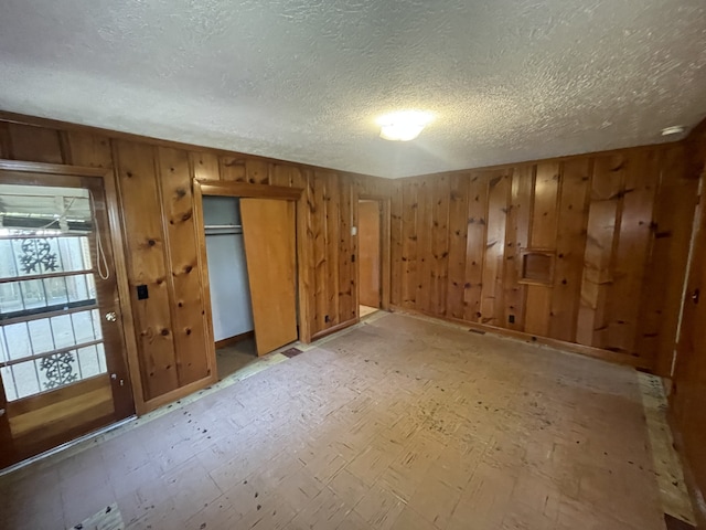 spare room with wood walls and a textured ceiling