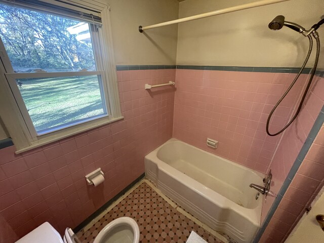 bathroom with tiled shower / bath, tile walls, and toilet