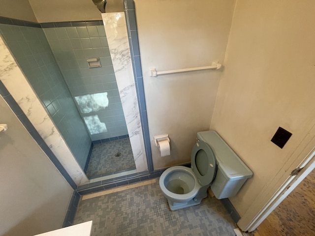 bathroom featuring a tile shower, toilet, and tile patterned floors