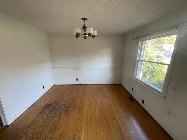 unfurnished dining area featuring hardwood / wood-style flooring, a textured ceiling, and a chandelier