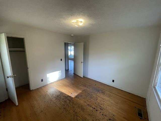 unfurnished bedroom with a closet, a textured ceiling, and hardwood / wood-style floors