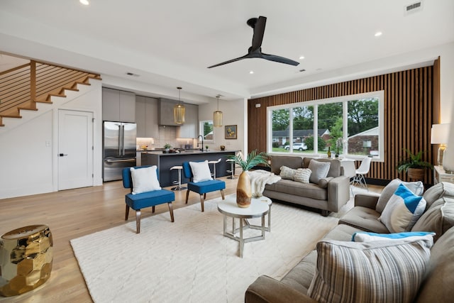 living room featuring light hardwood / wood-style floors, sink, and ceiling fan