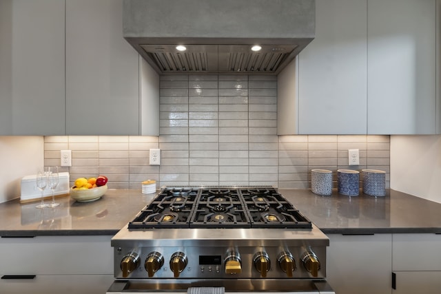 kitchen with decorative backsplash, exhaust hood, stainless steel range, and white cabinets