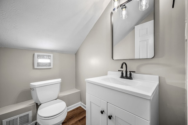 bathroom with toilet, vanity, lofted ceiling, and hardwood / wood-style floors